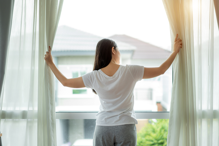 Woman opening window curtains